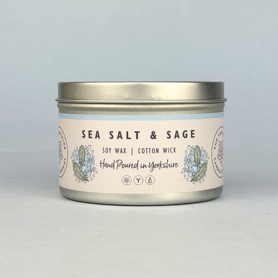 Candle tin labeled 'Sea Salt & Sage' on a light gray background