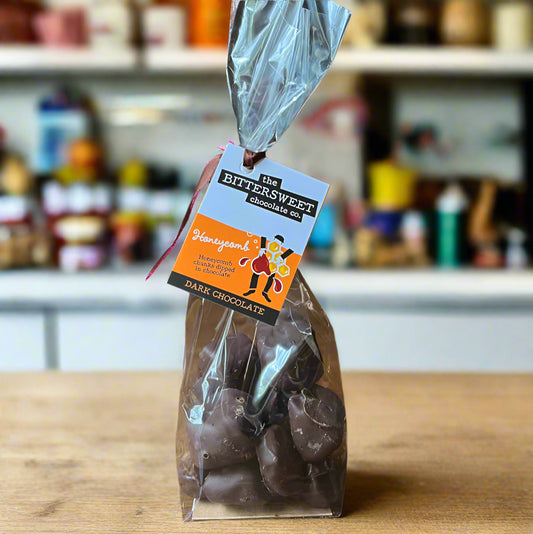 Bag of dark chocolate covered cinder toffee with a 'Bittersweet Chocolates' label on a wooden surface.