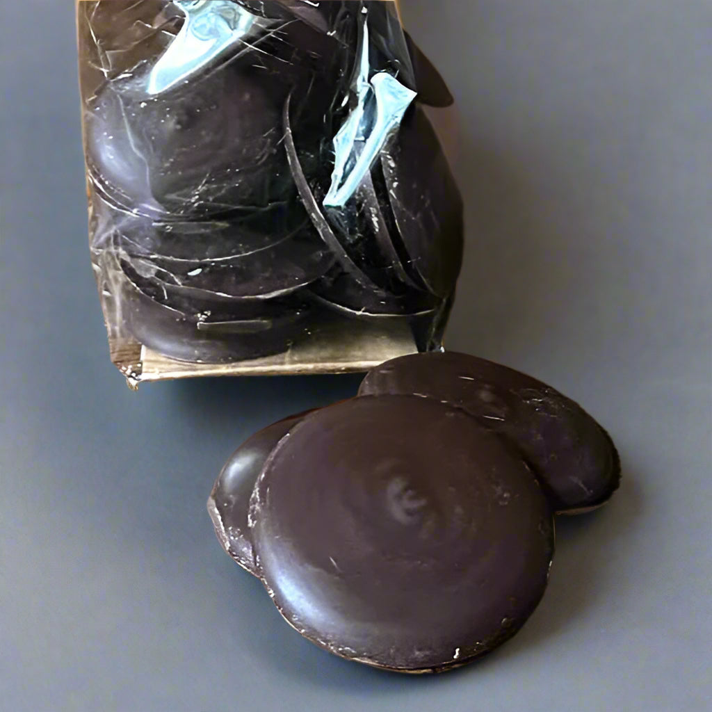 Dark chocolate buttons in a clear plastic bag on a wooden surface