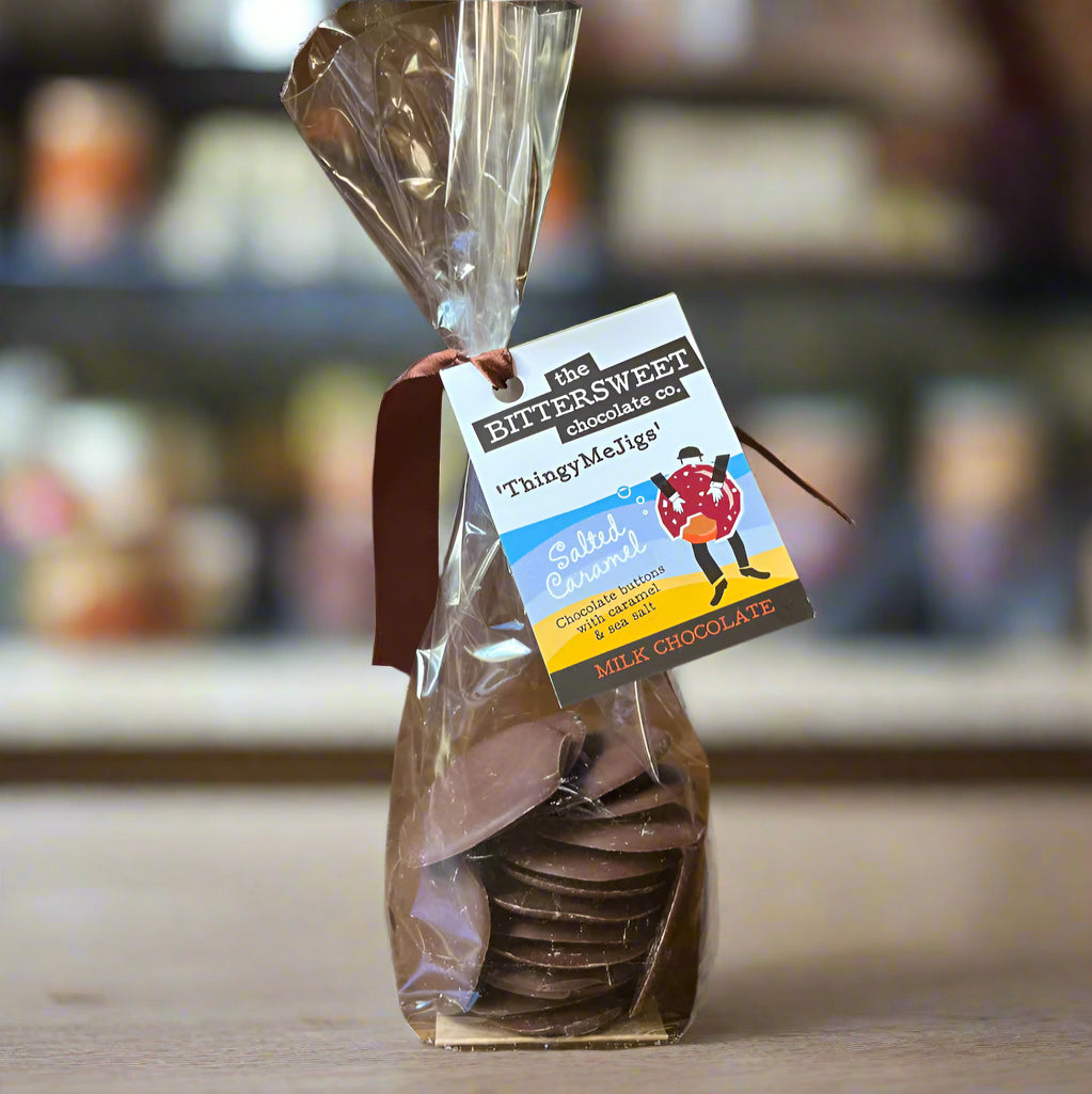Packaged chocolate discs with a tag on a wooden surface