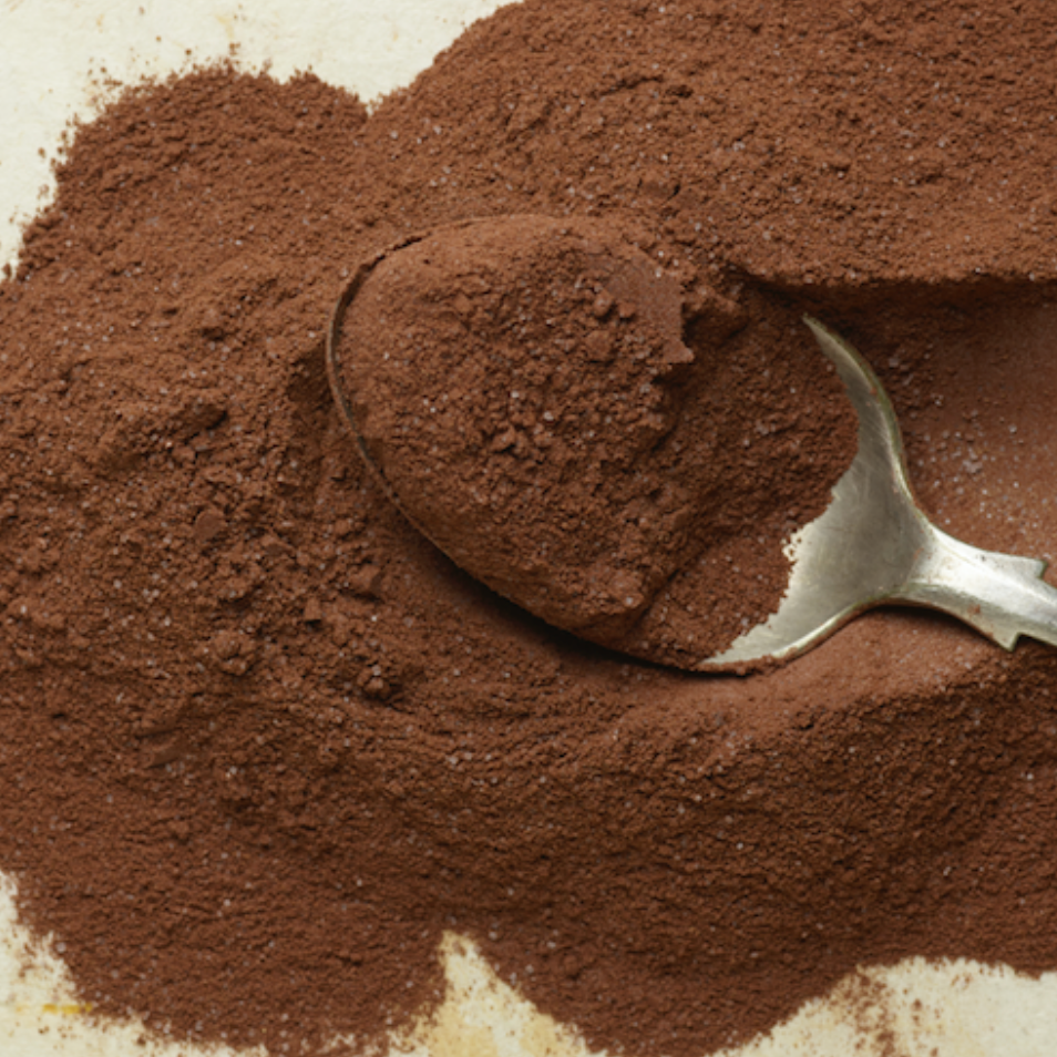 Cocoa powder with a spoon on a textured surface