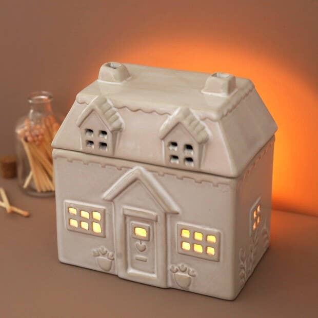 Ceramic house-shaped light with glowing windows on a warm-toned background