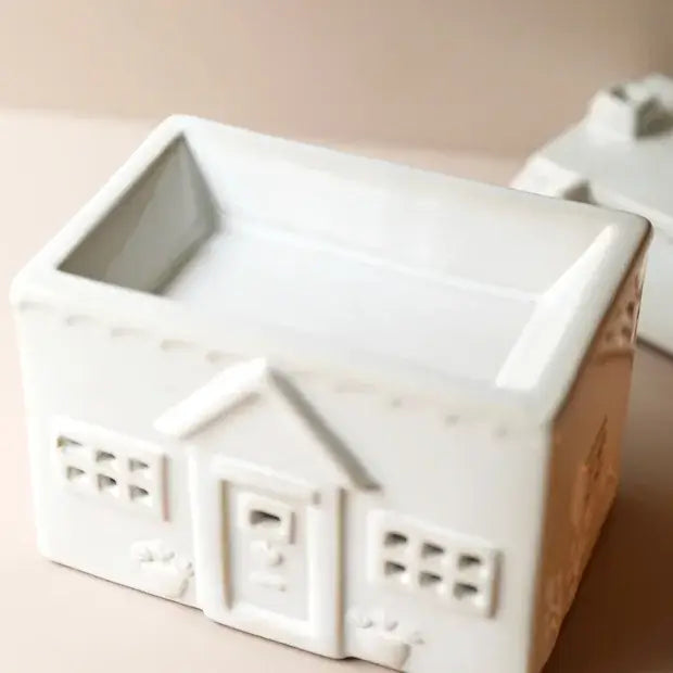 White ceramic house-shaped planter on a beige background