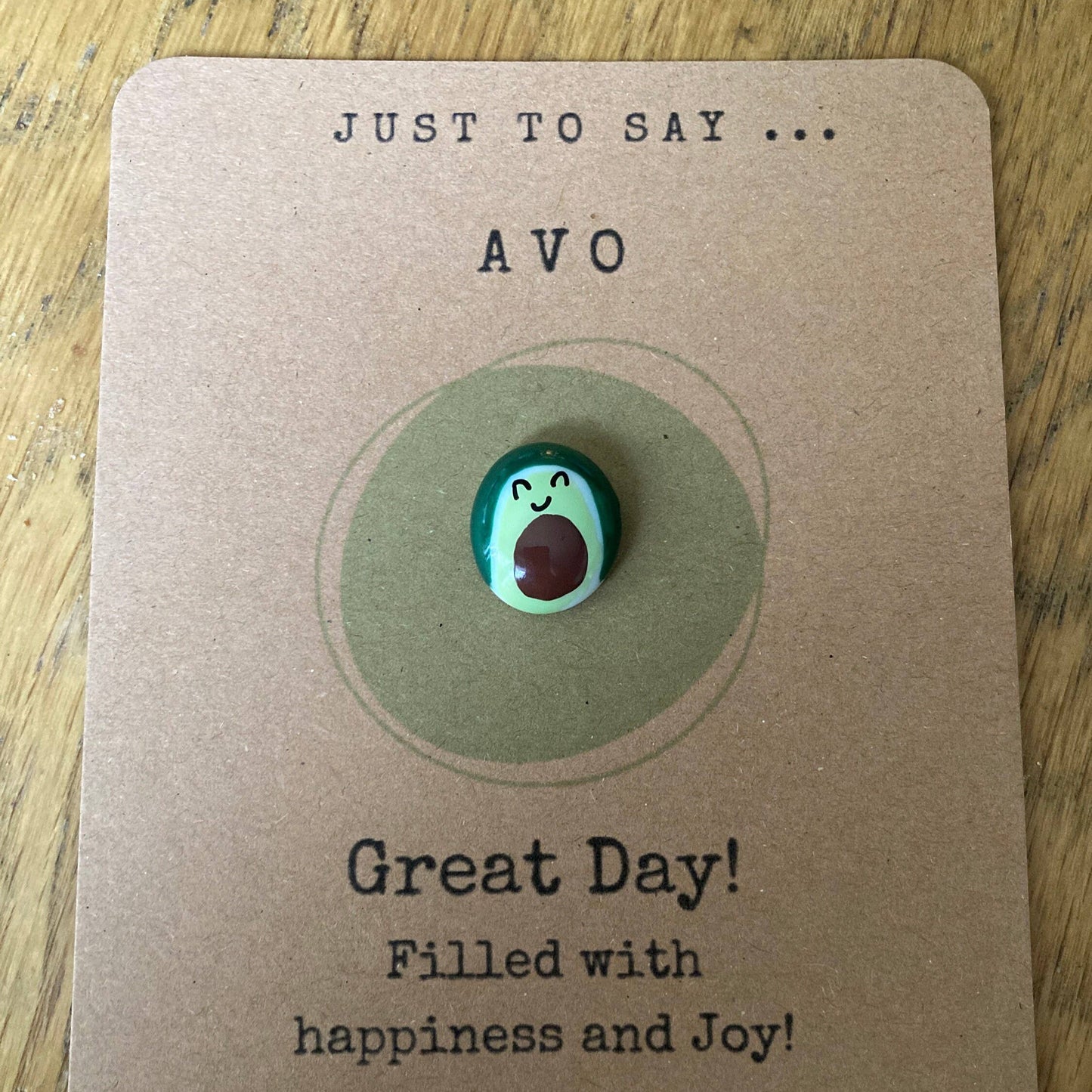 Avocado-shaped charm on a card with text and a website URL.