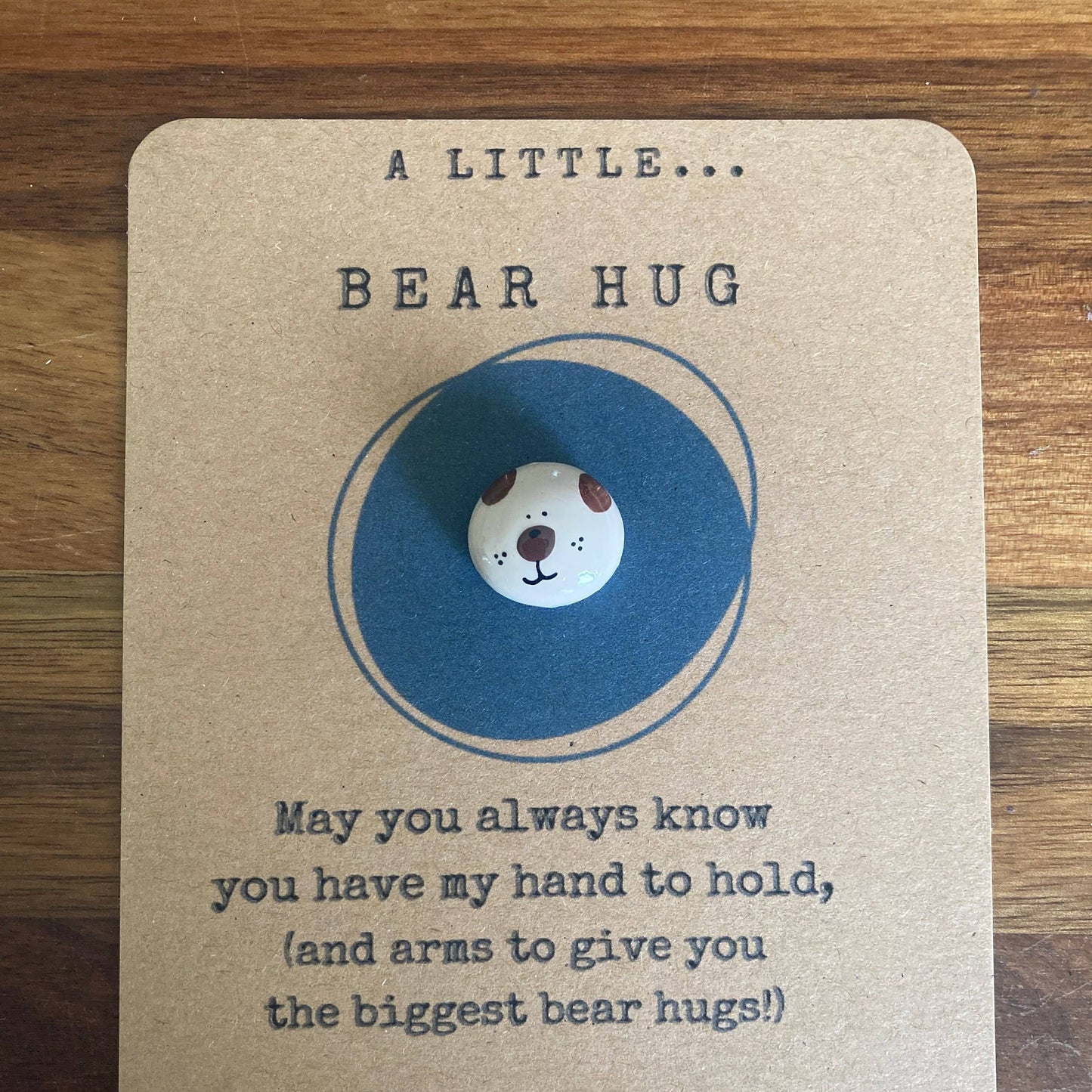 Card with a bear-shaped button and text on a wooden surface