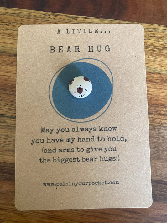 Card with a bear charm and text on a wooden surface