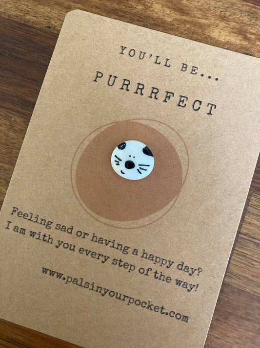 Kraft paper card with a pebble and text on a wooden surface