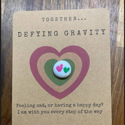 Card with green and pink heart design and text on a wooden surface