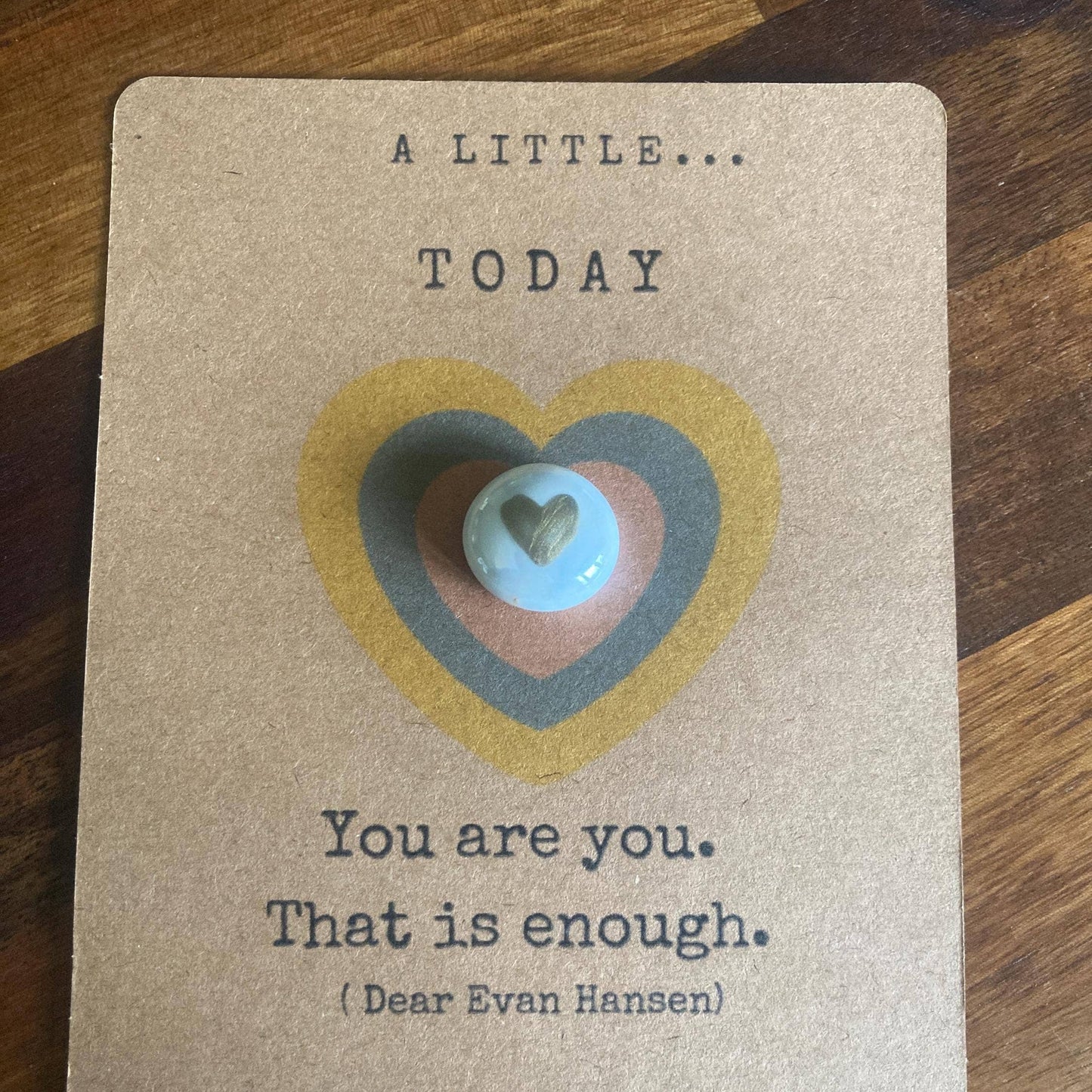 Card with heart design and motivational quote on a wooden surface