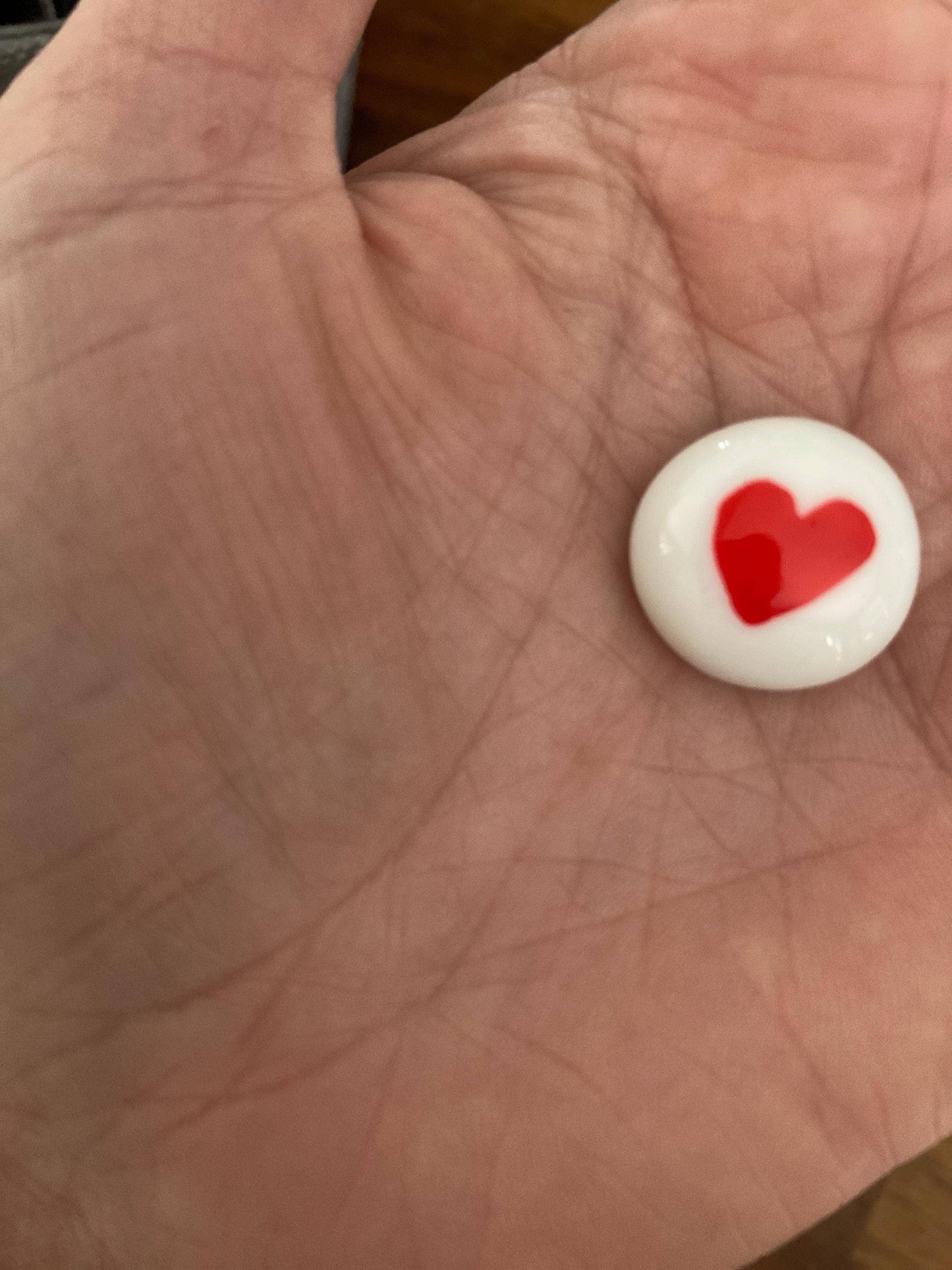 Small white token with a red heart on a hand