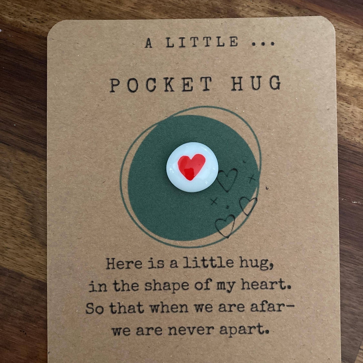 Card with a pebble featuring a heart design on a wooden surface