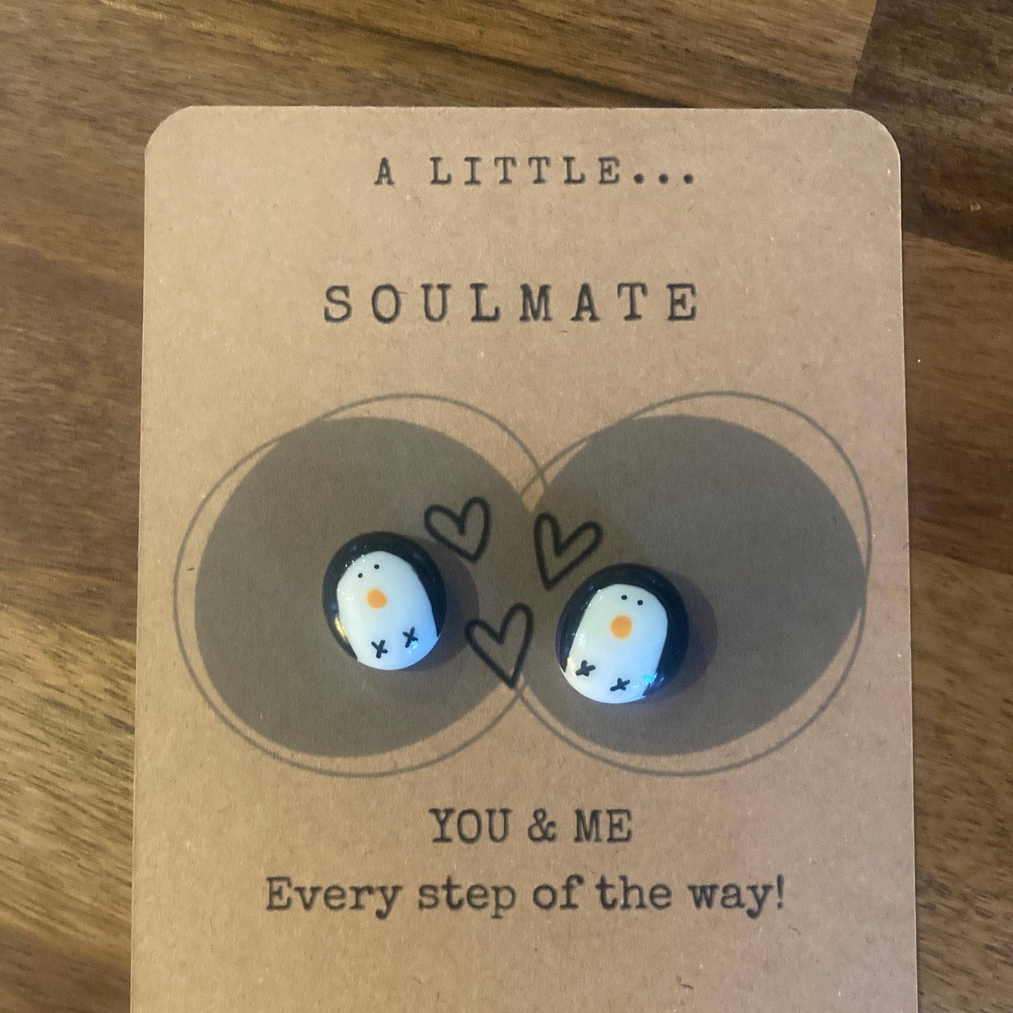 Pair of penguin earrings on a 'A Little Soulmate' card with hearts and text.