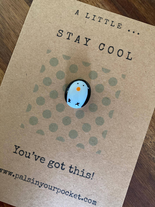 Charm with a blue character on a brown card with text and website URL