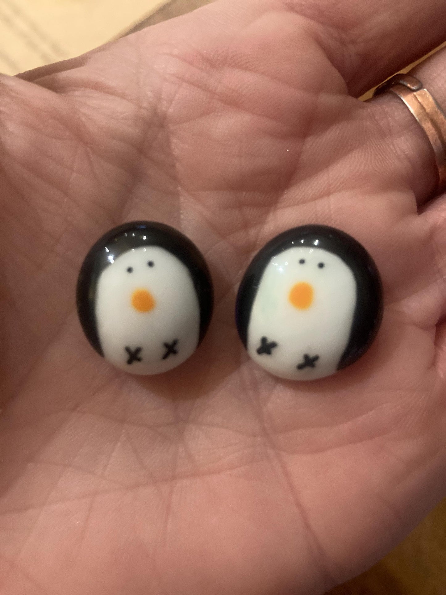Two penguin-shaped tokens on a person's palm.