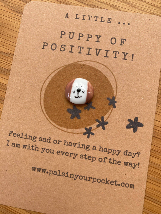 Puppy-shaped stress charm on a brown card with text and website URL.