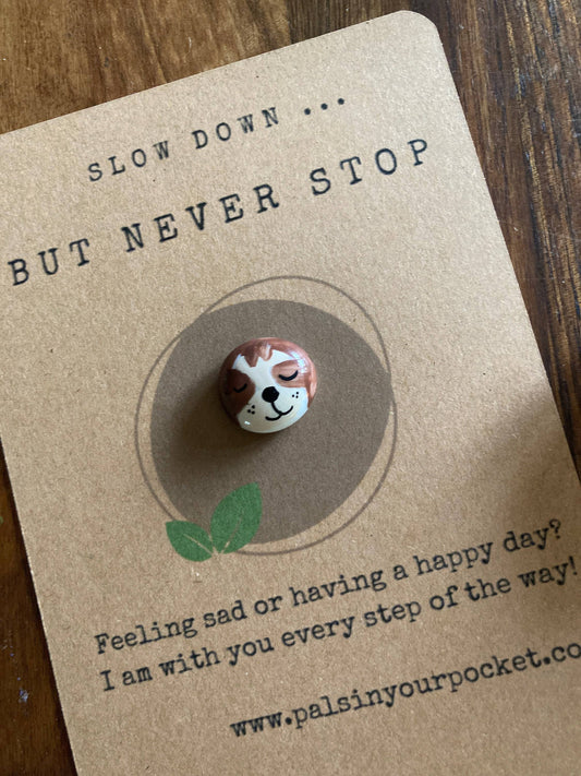 Card with a small figurine of a sloth and text on a wooden surface