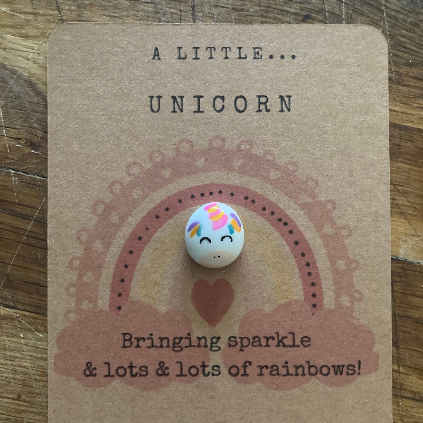 Unicorn-themed token on a brown card with text on a wooden surface