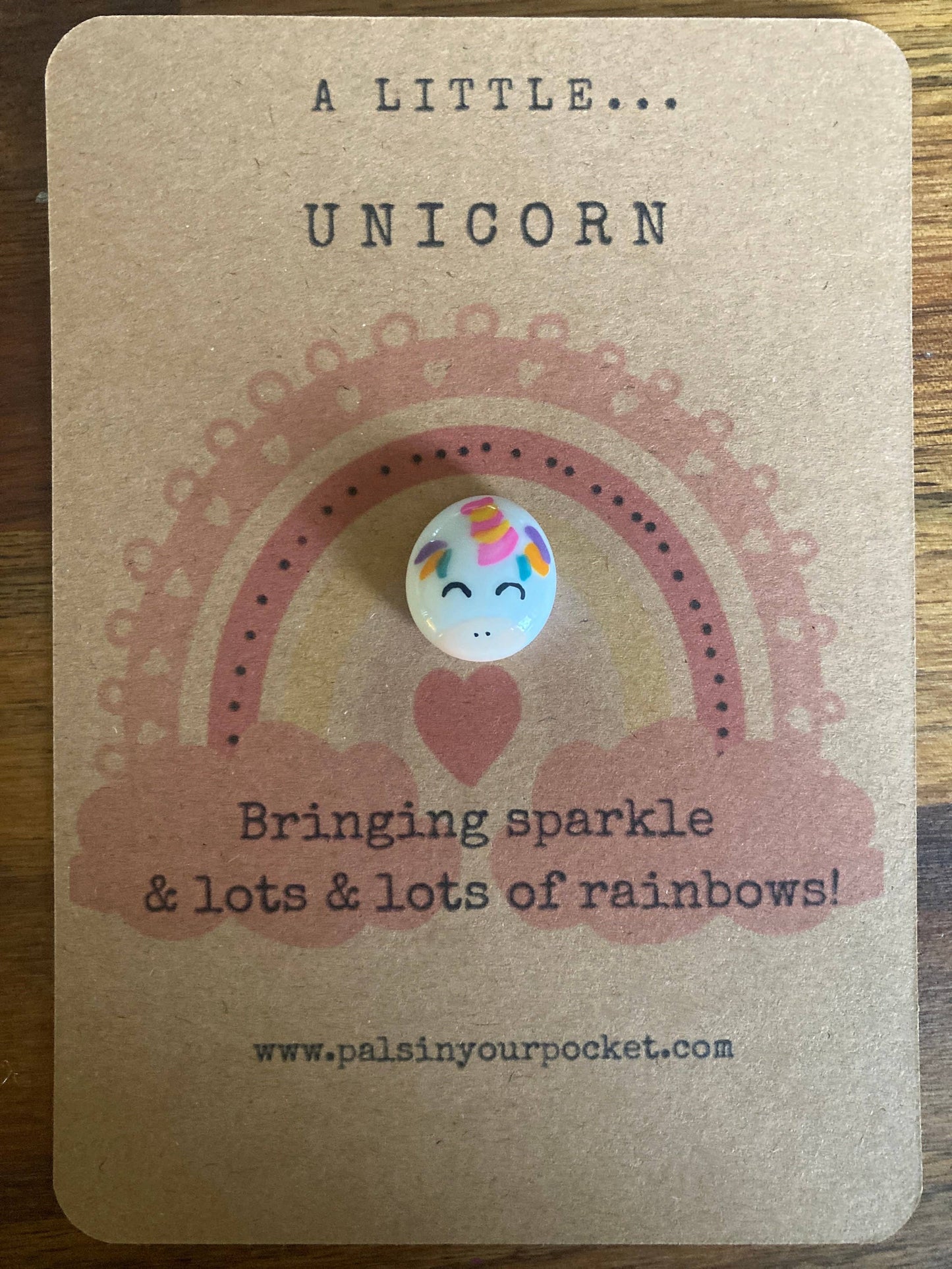 Unicorn charm on a kraft paper card with text and rainbow design
