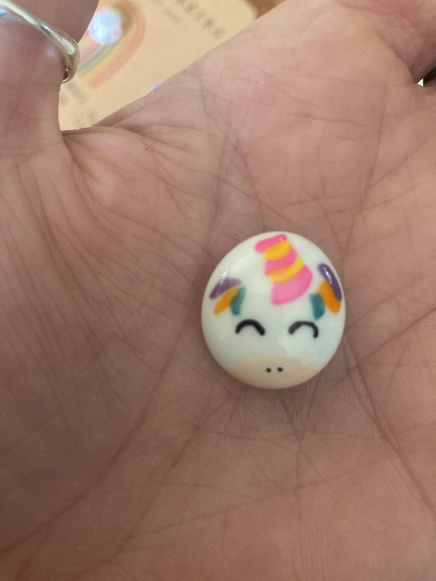 Small round object with a unicorn design on a person's palm