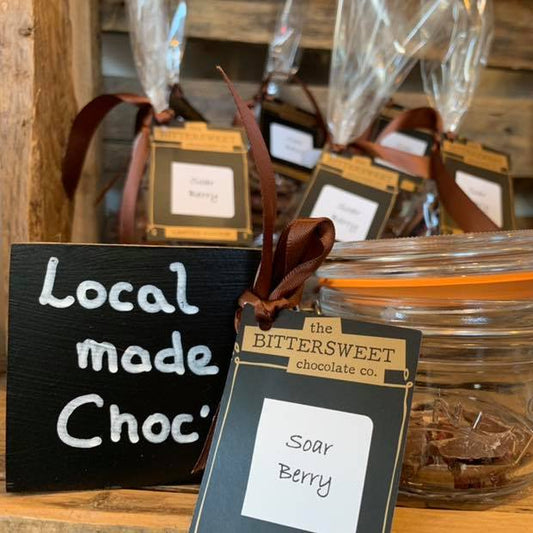 Jar of 'Soar Berry' chocolate with 'Bittersweet Chocolate Co.' packaging on a wooden surface.