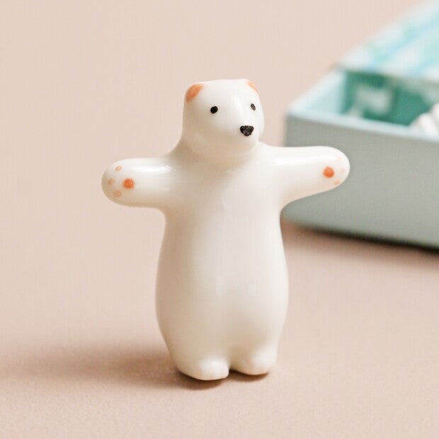 Small white polar bear figurine on a beige surface