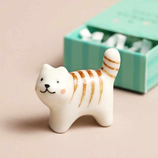 Ceramic cat figurine with gold stripes on a beige background