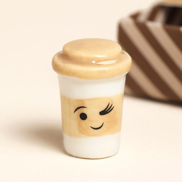 Small ceramic cup with a smiley face design on a beige background