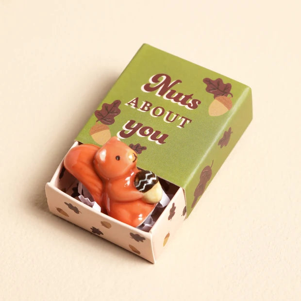 Lisa Angel ceramic squirrel token nestled in crinkled paper inside the Nuts About You matchbox