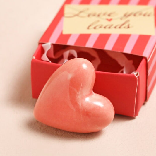 Heart-shaped pink token in a red striped box with 'Love you loads' text