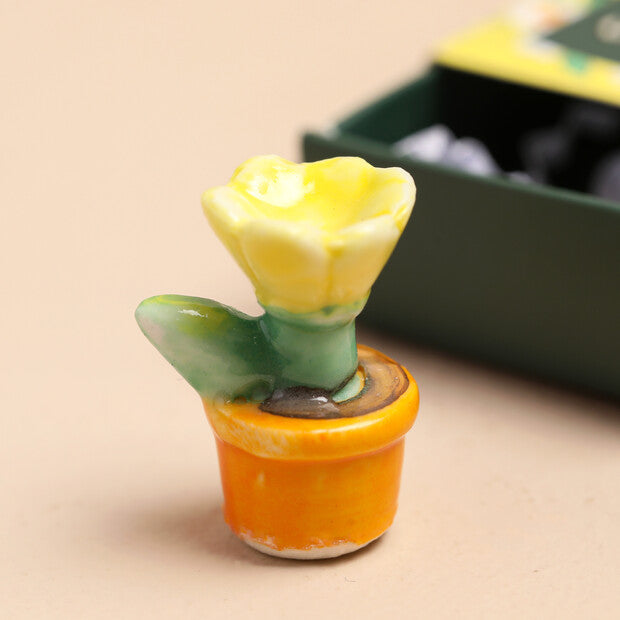 Small ceramic cactus with a yellow flower in an orange pot on a beige background