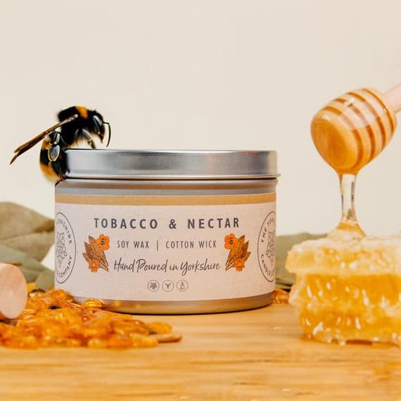 Candle labeled 'Tobacco & Nectar' with a bee and honeycomb on a wooden surface