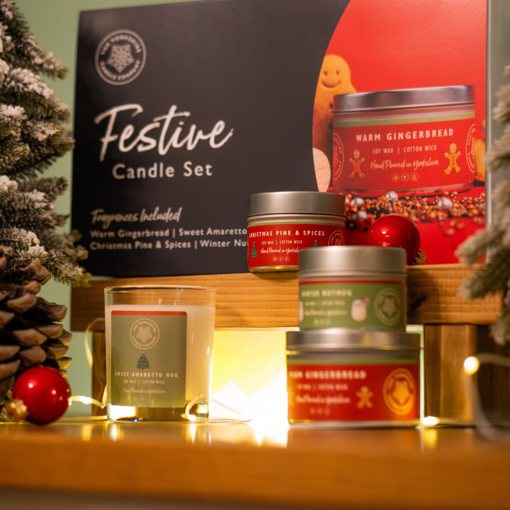 Festive candle gift set displayed with four candles, its presentation box and Christmas decorations