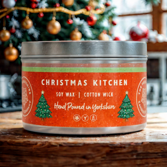 Candle in a tin labeled 'Christmas Kitchen' with a festive background