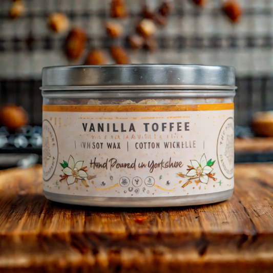 Vanilla toffee candle in a tin on a wooden surface with blurred background