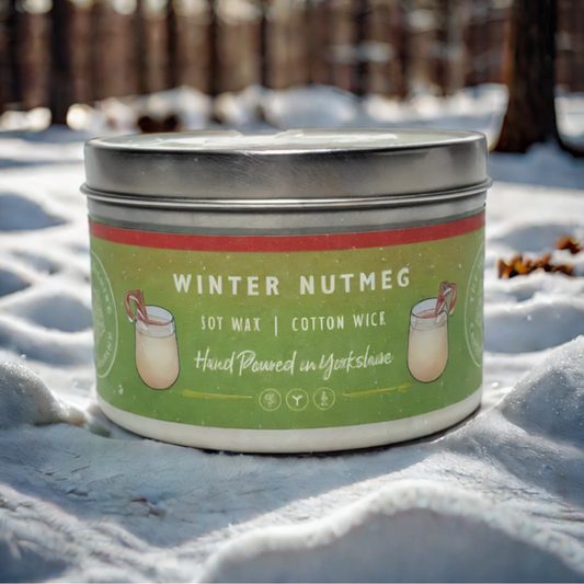 Candle tin labeled 'Winter Nutmeg' in the snow