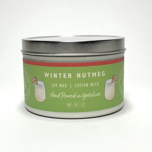 Candle tin labeled 'Winter Nutmeg' with a green label on a white background
