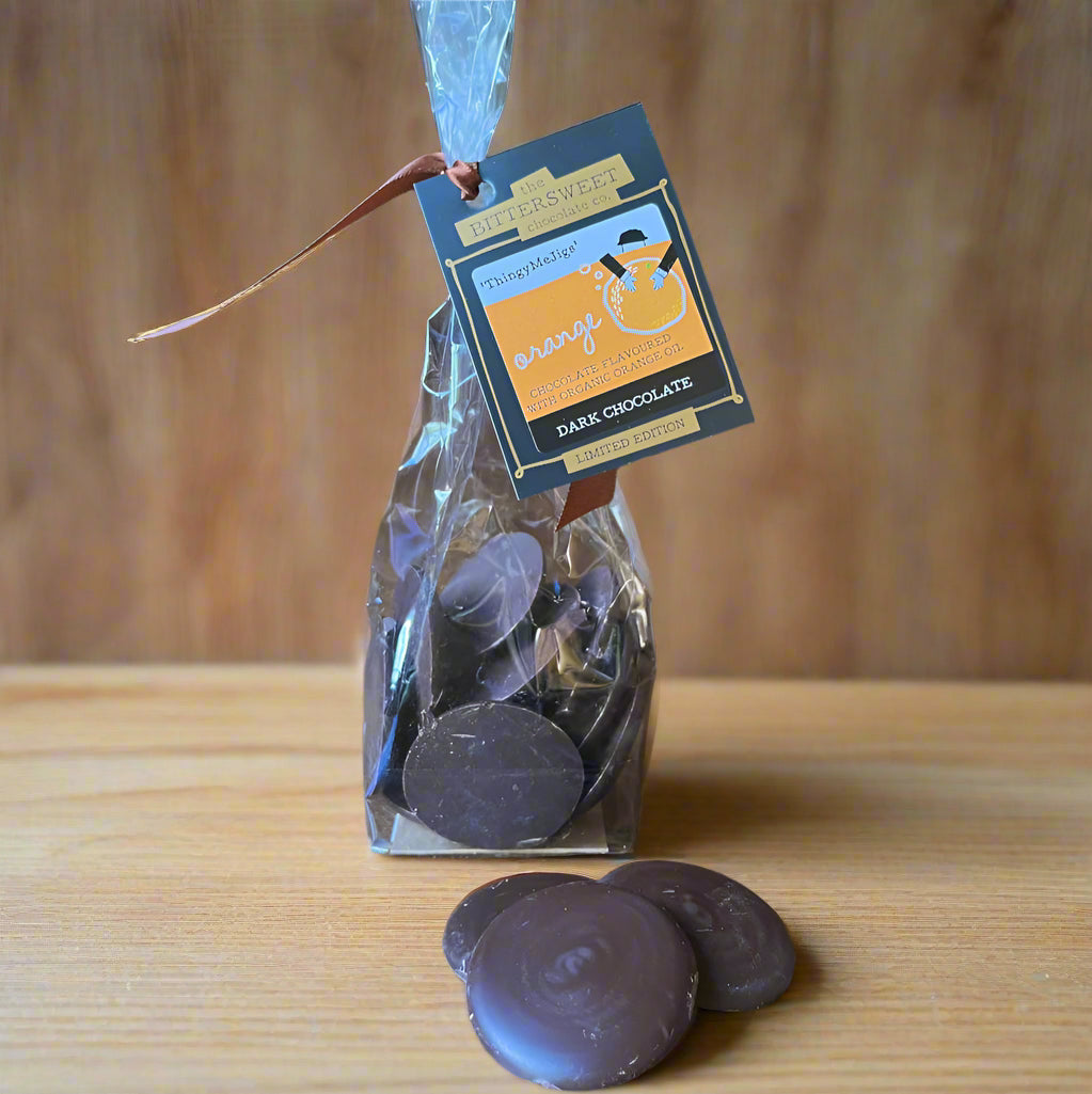Bag of dark chocolate coins with a tag on a wooden surface