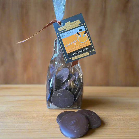 Bag of dark chocolate coins with a tag on a wooden surface