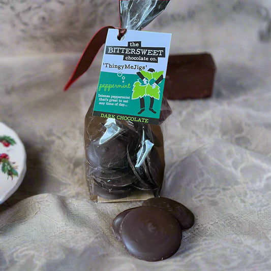 Packaged dark chocolate peppermint buttons with a visible brand tag on a wooden surface.