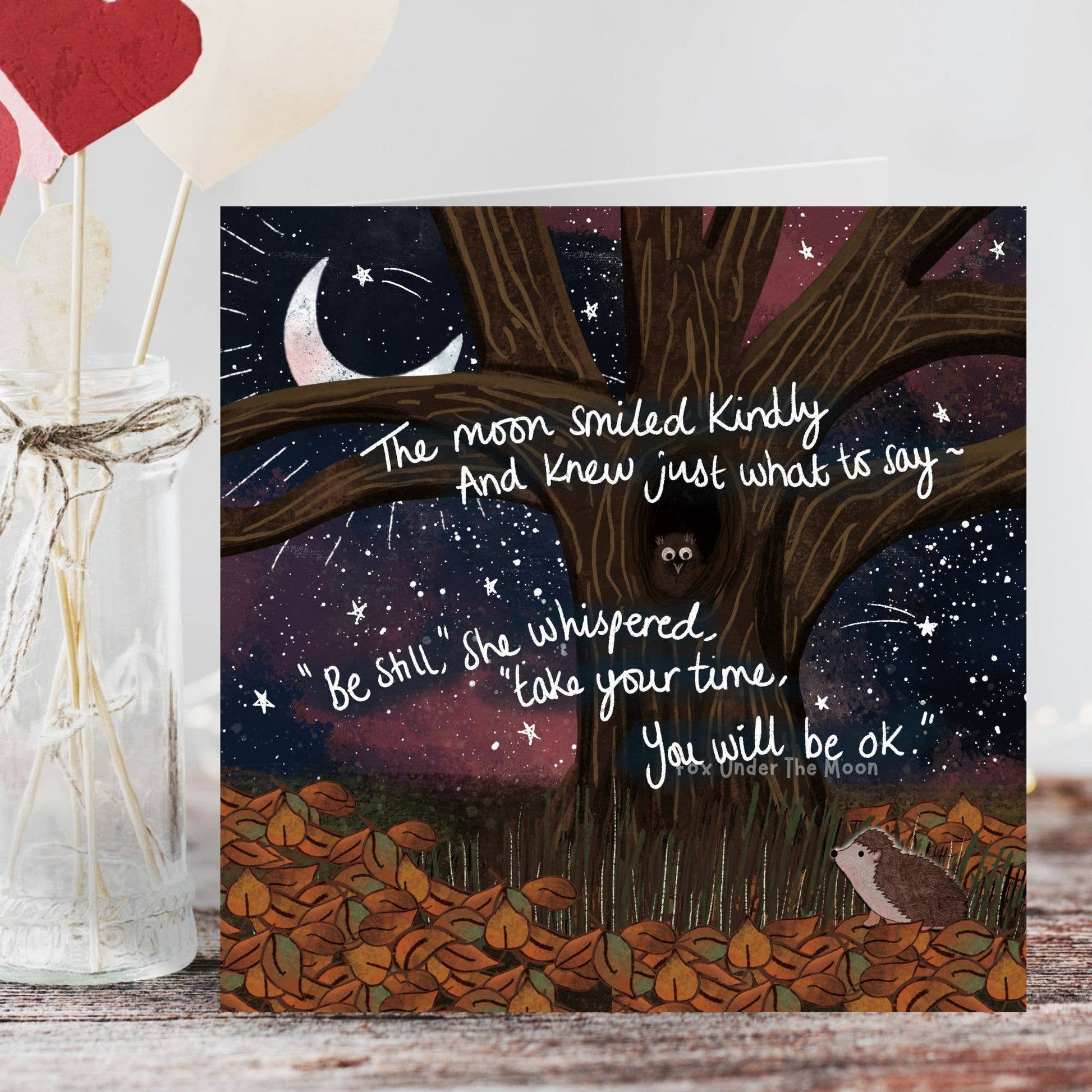 Illustration of a tree with a moon and stars, featuring a quote and a small animal, on a wooden surface.