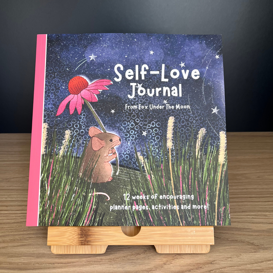 Self-Love Journal titled 'From Fox Under the Moon' on a wooden stand with a dark background