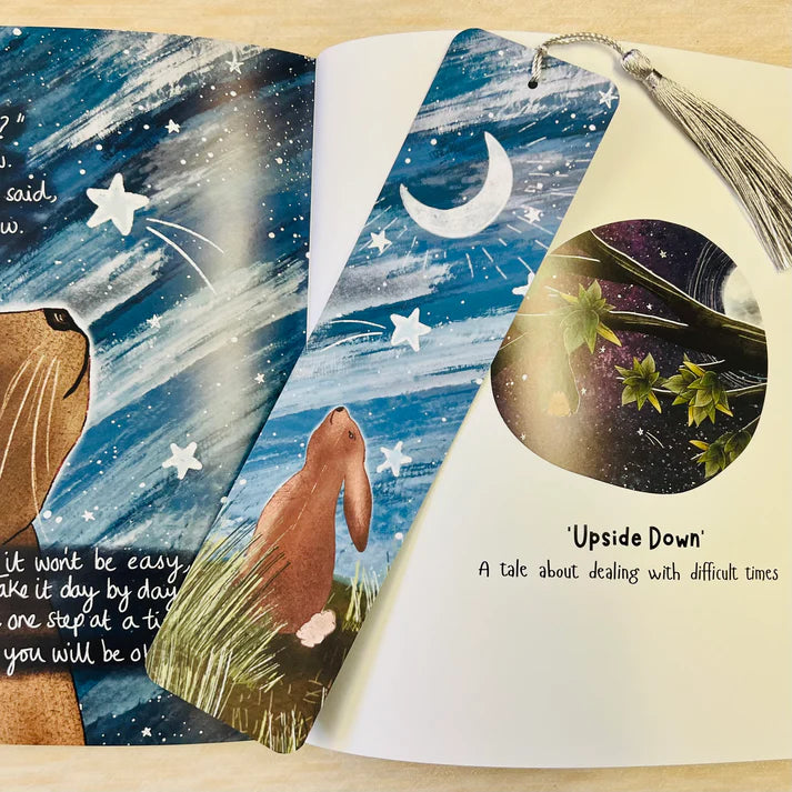 Children's book open to a page with illustrations of a rabbit, stars, and a moon, with text about dealing with difficult times.