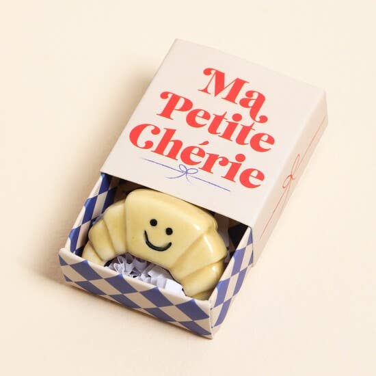 Smiley face croissant token in a 'Ma Petite Chérie' box on a beige background