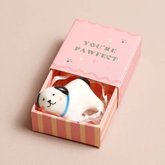 Dog-shaped figurine in a pink box with 'YOU'RE PAWFECT' text on a beige background