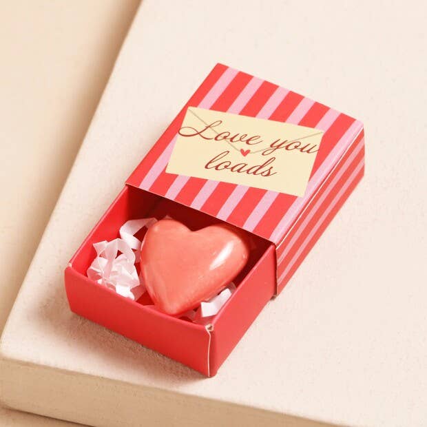 Heart-shaped pink soap in a red and white striped box with 'Love you loads' text on a beige background