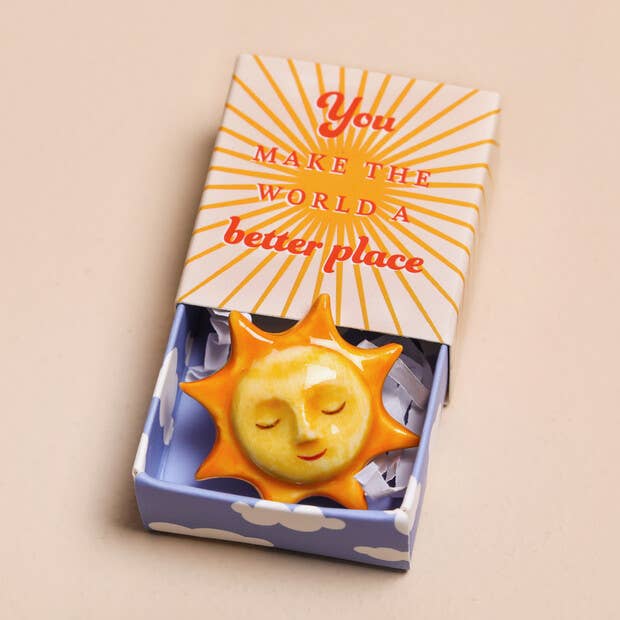 Decorative sun ornament in a box with a motivational quote on a beige background