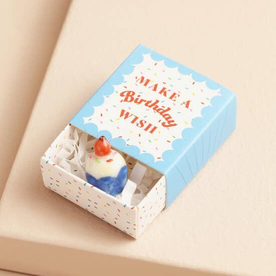Small cake-shaped token in a decorative box with 'Make a Birthday Wish' text on a beige background