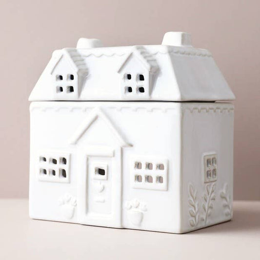 White ceramic house-shaped container on a light pink background