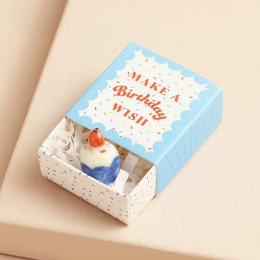 Small cake-shaped charm in a decorative box with 'Make a Birthday Wish' text on a beige background