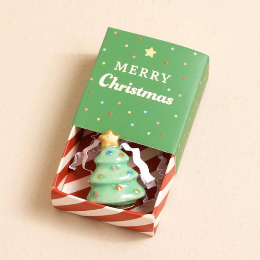 Christmas tree-shaped token in a decorative box with 'Merry Christmas' text on a beige background